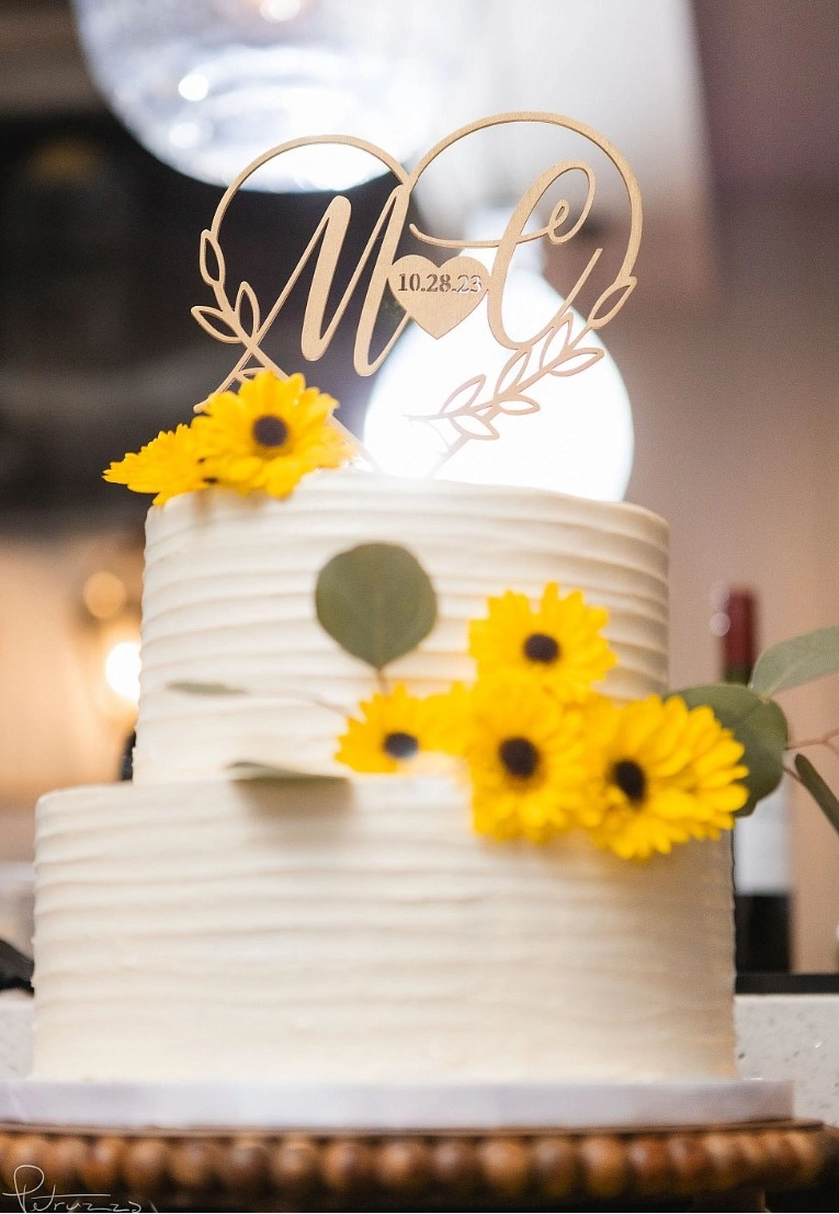 A tiered wedding cake dressed with fresh sunflowers and eucalyptus