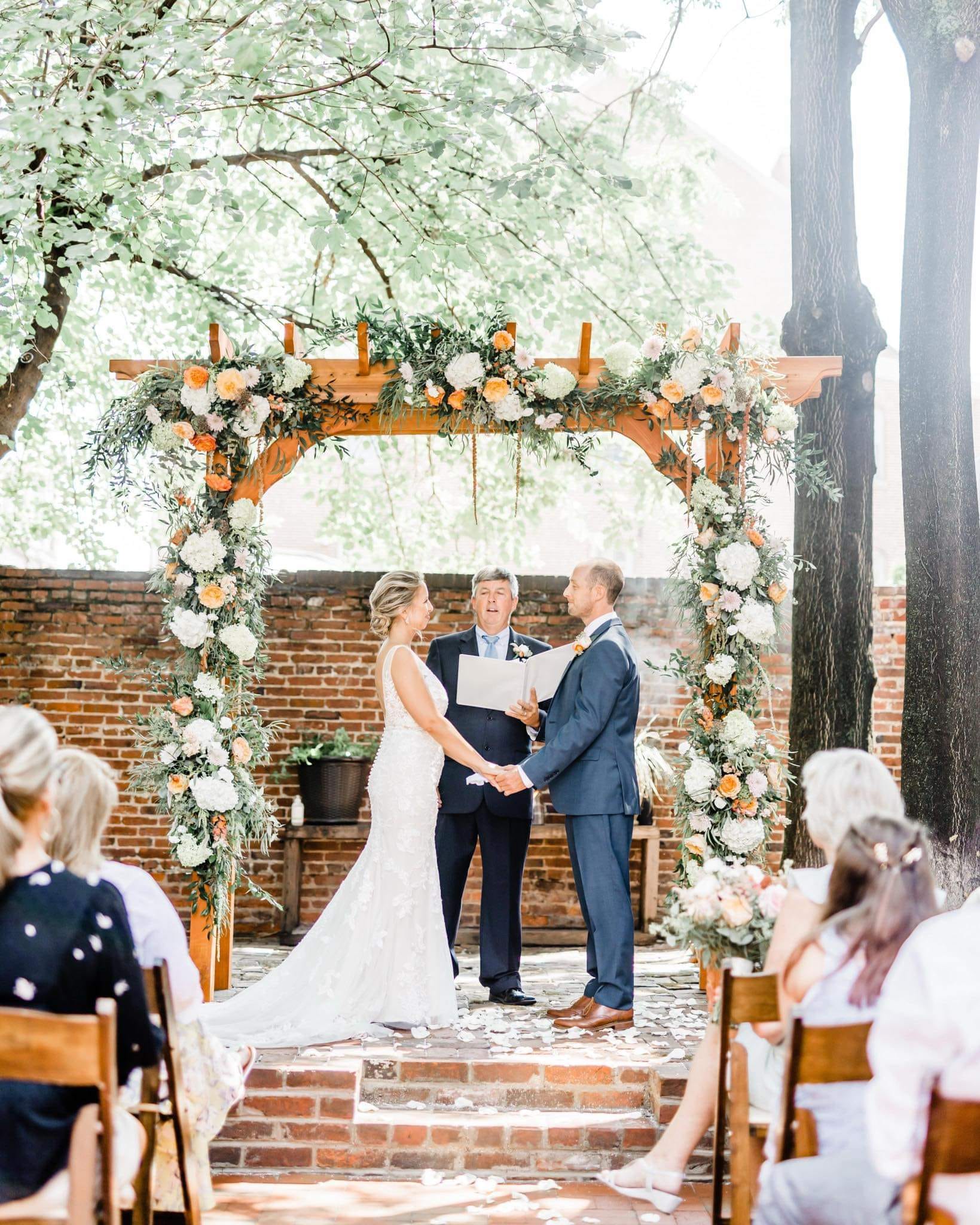 Outdoor ceremony arch dressed with peach and white roses
