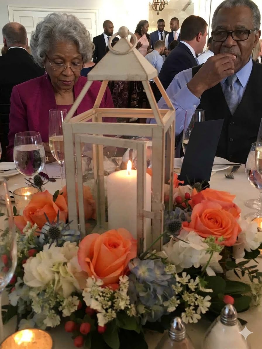 A lantern centrepiece ringed with orange roses, blue hydrangea and red hypericum berries on a candlelit table