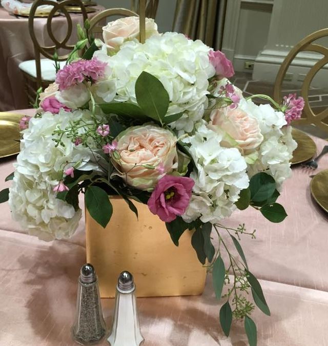A gold box centrepiece of white hydrangea, blush garden roses and pink lisianthus on blush linen