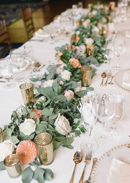 Head table run with a eucalyptus and rose garland, gold votives and peach dahlias