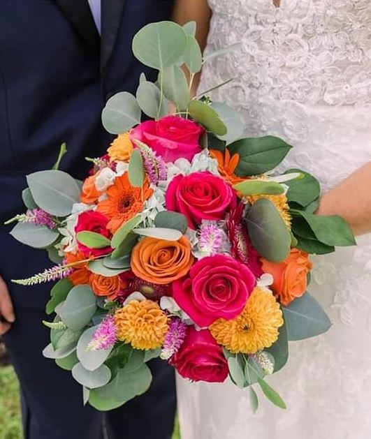 A vibrant bouquet of hot pink and orange roses, gerbera and marigold chrysanthemums